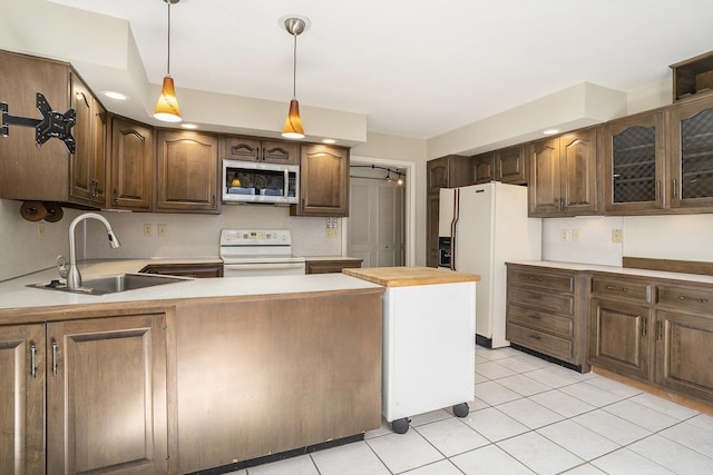 kitchen featuring white appliances, light tile patterned flooring, a sink, light countertops, and decorative light fixtures