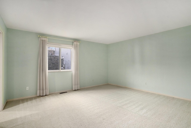 carpeted spare room with visible vents and baseboards