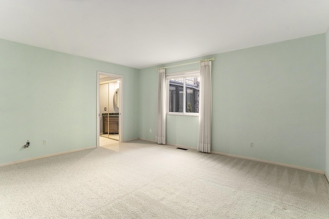 empty room with visible vents, light colored carpet, and baseboards