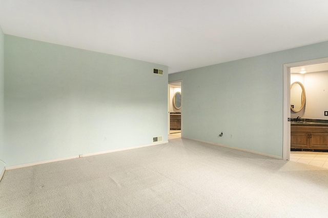 unfurnished room with visible vents, light colored carpet, and baseboards