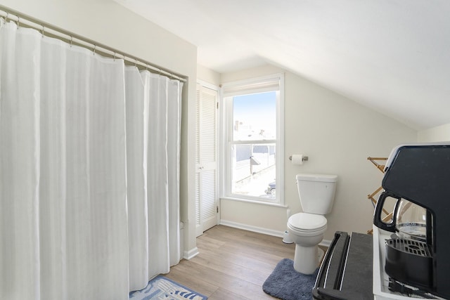 full bathroom with vaulted ceiling, toilet, baseboards, and wood finished floors