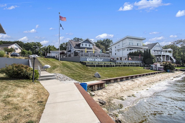 dock area with a water view, a lawn, and stairs