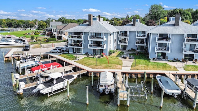 view of dock featuring a water view, boat lift, and a lawn