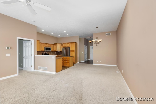 kitchen featuring hanging light fixtures, decorative backsplash, light brown cabinetry, light colored carpet, and stainless steel appliances