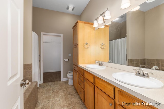 bathroom featuring vanity, a bath, and toilet