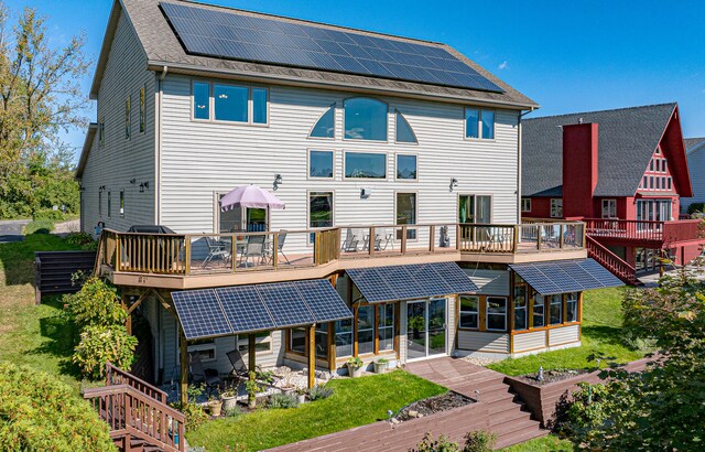 back of house with a lawn, a wooden deck, and solar panels