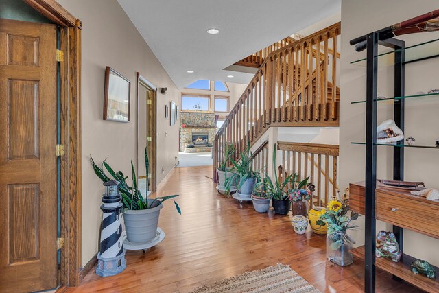 entrance foyer featuring vaulted ceiling, a fireplace, and light hardwood / wood-style floors