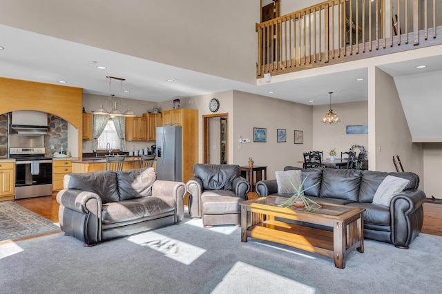 living area with light carpet, an inviting chandelier, a towering ceiling, and recessed lighting