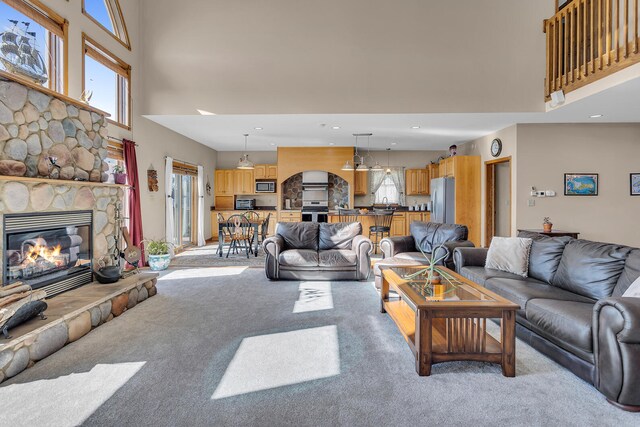 carpeted living room with a stone fireplace and a towering ceiling