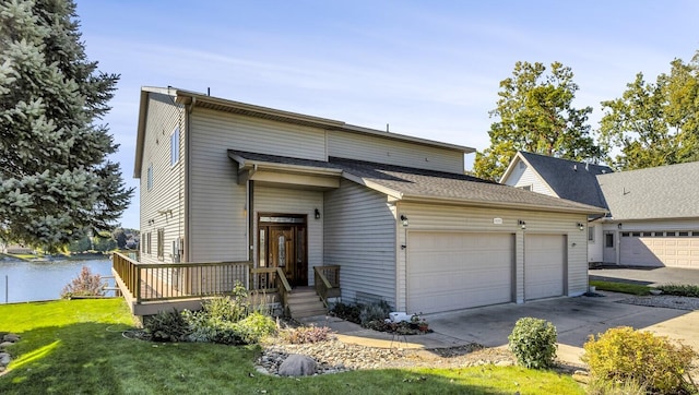 view of front of home featuring a water view, driveway, an attached garage, and a front lawn