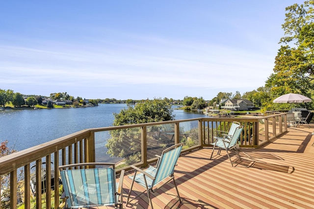 deck with outdoor dining area and a water view