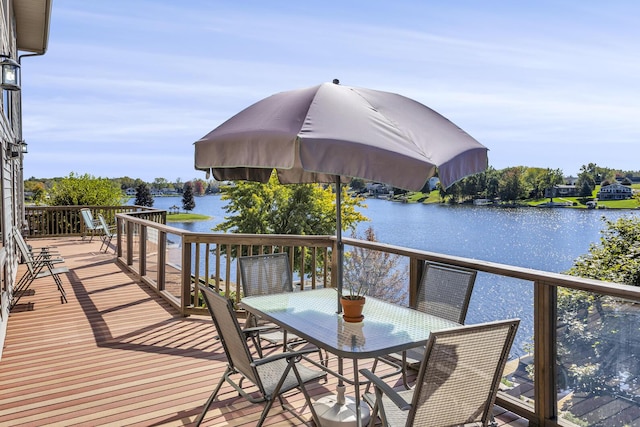wooden deck with a water view and outdoor dining space