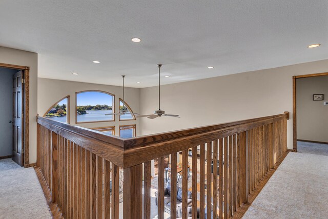 corridor featuring light carpet, a textured ceiling, and a water view