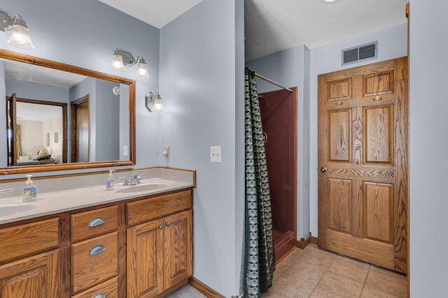 bathroom with tile patterned flooring, walk in shower, and vanity