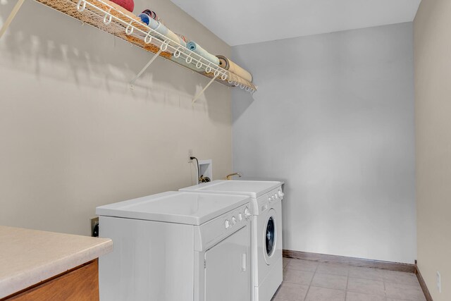 laundry area with light tile patterned floors and washing machine and clothes dryer