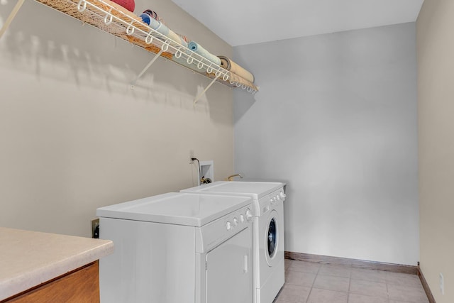 laundry room featuring light tile patterned floors, baseboards, separate washer and dryer, and laundry area