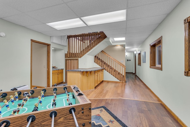 rec room with wood-type flooring and a drop ceiling