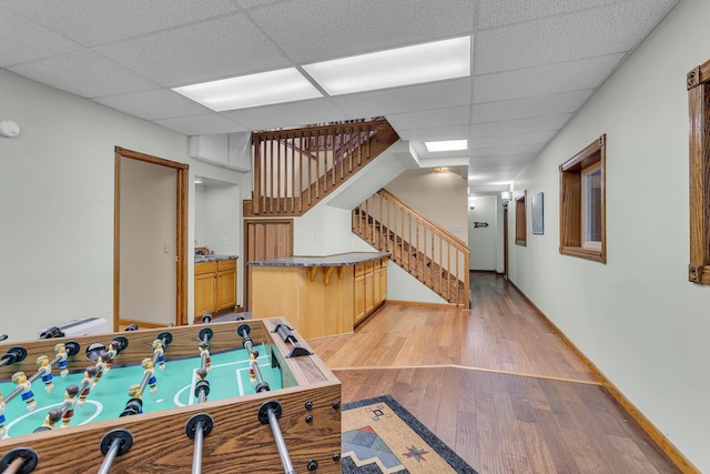 playroom featuring a paneled ceiling, baseboards, and light wood-style flooring