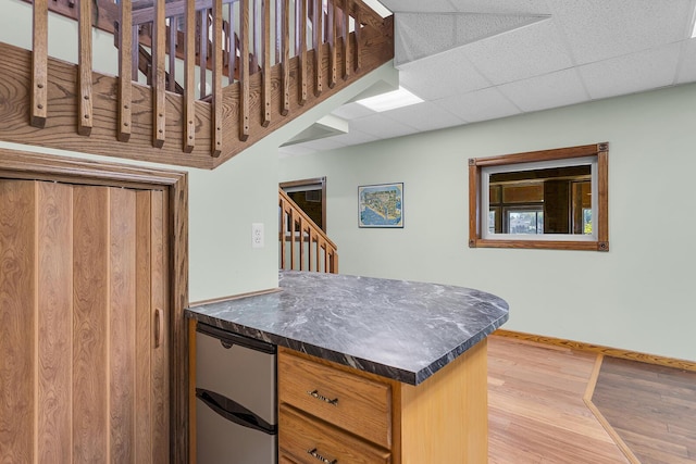 kitchen featuring dark countertops, baseboards, wood finished floors, and fridge