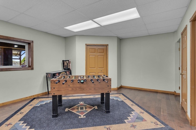 rec room with wood finished floors, a paneled ceiling, and baseboards