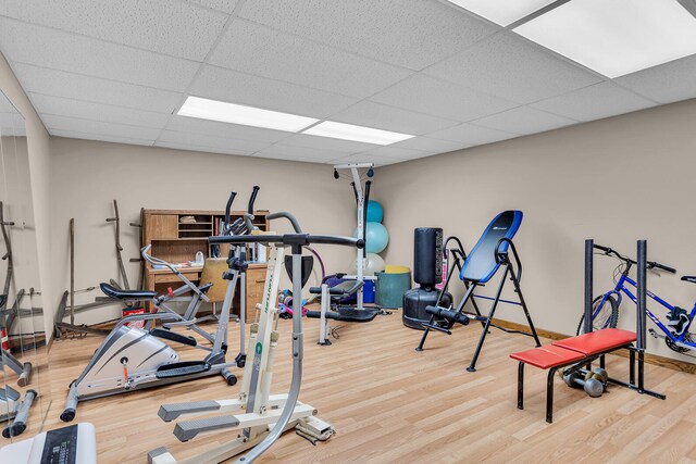 exercise room featuring wood-type flooring and a drop ceiling