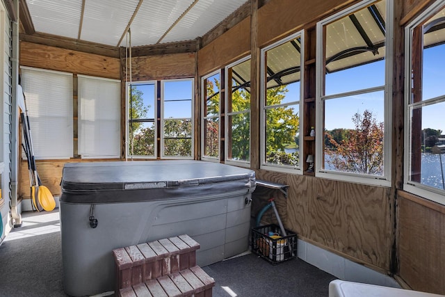 sunroom / solarium with plenty of natural light, a hot tub, and carpet