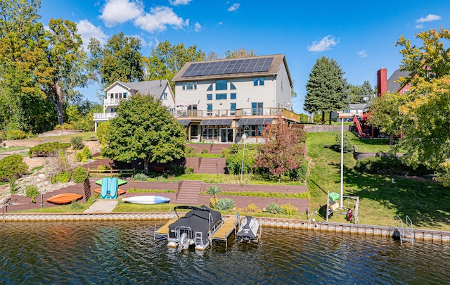 back of property with a water view and a lawn