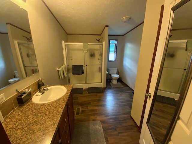 bathroom featuring vanity, a textured ceiling, hardwood / wood-style flooring, toilet, and a shower with door