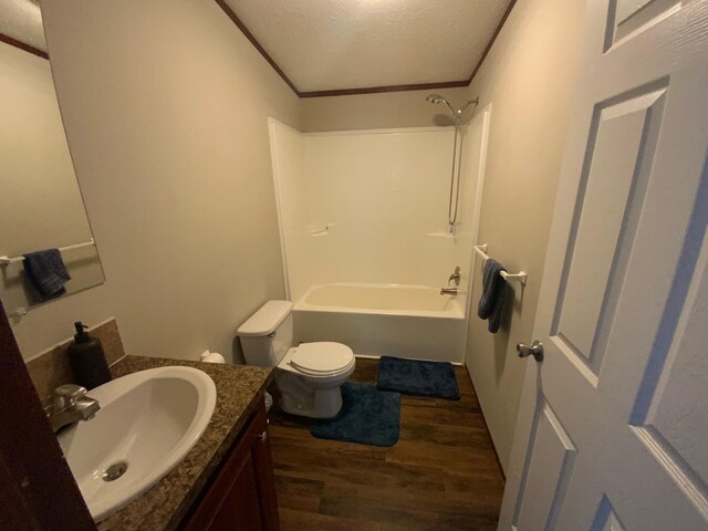 full bathroom featuring a textured ceiling, hardwood / wood-style flooring, bathing tub / shower combination, vanity, and toilet