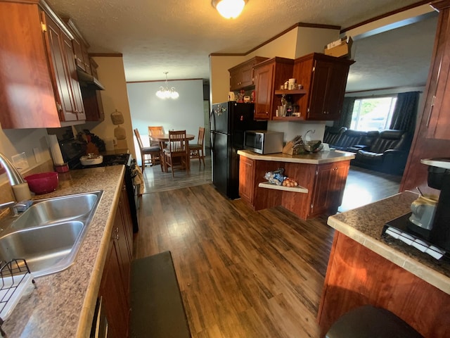 kitchen with appliances with stainless steel finishes, dark wood-type flooring, pendant lighting, a textured ceiling, and ornamental molding