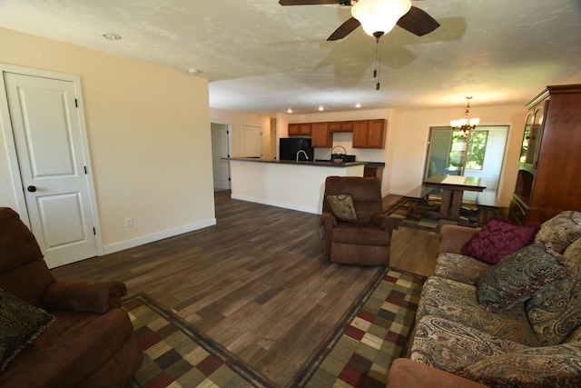 living room featuring ceiling fan with notable chandelier, dark hardwood / wood-style floors, and sink