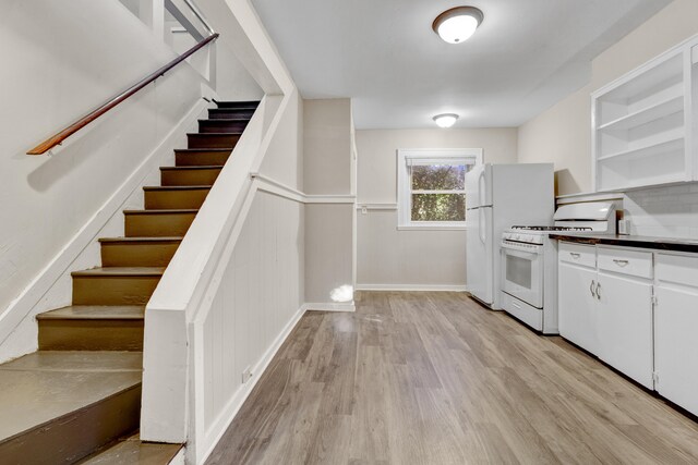 kitchen featuring gas range gas stove, white cabinetry, light hardwood / wood-style floors, and backsplash