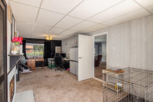 carpeted office space featuring a drop ceiling and wood walls