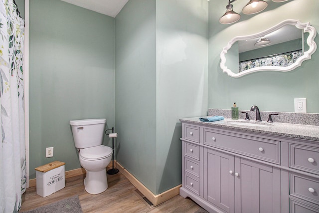 bathroom with hardwood / wood-style floors, vanity, and toilet