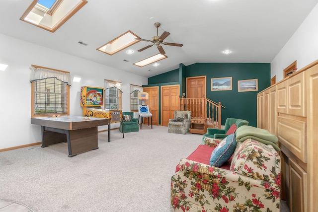 living room with ceiling fan, vaulted ceiling with skylight, and carpet flooring