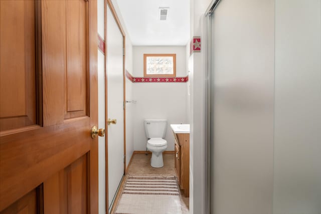 bathroom with walk in shower, vanity, tile patterned flooring, and toilet