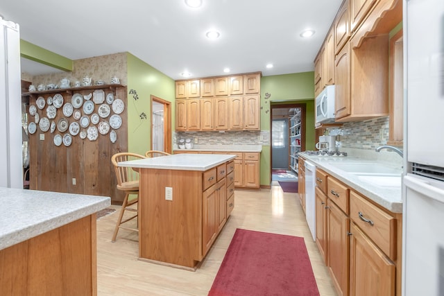 kitchen with a breakfast bar, light hardwood / wood-style floors, white appliances, and a kitchen island