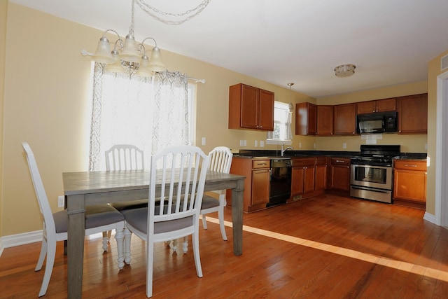 kitchen with pendant lighting, dark wood-type flooring, a chandelier, and black appliances