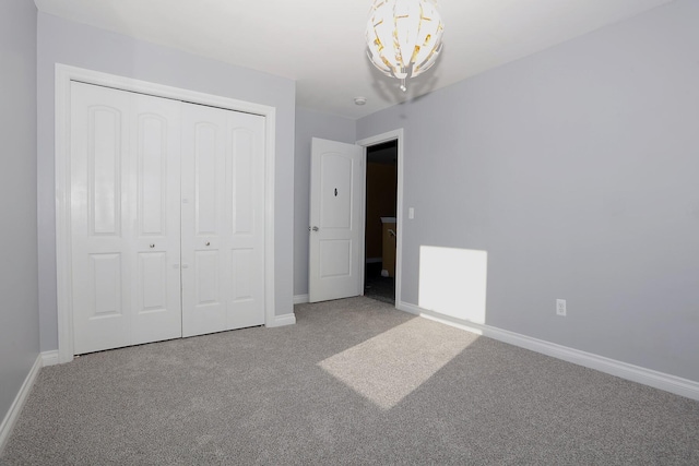 unfurnished bedroom featuring carpet floors, a closet, and a chandelier