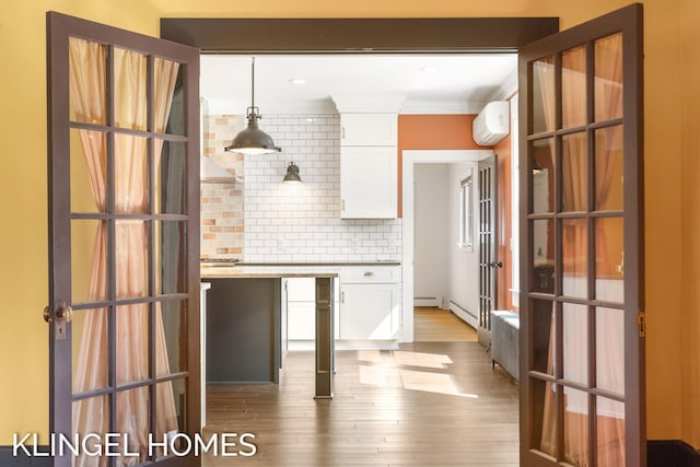 kitchen featuring white cabinets, pendant lighting, hardwood / wood-style flooring, decorative backsplash, and a wall unit AC