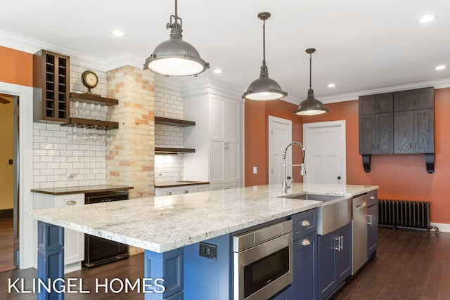 kitchen with sink, radiator, a center island with sink, decorative light fixtures, and dark hardwood / wood-style flooring