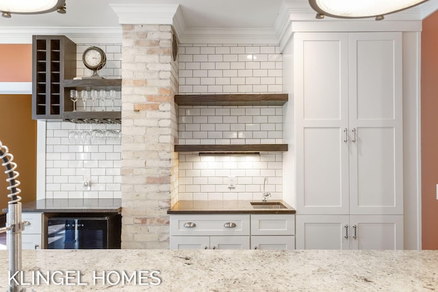 kitchen with backsplash, ornamental molding, light stone counters, and white cabinets