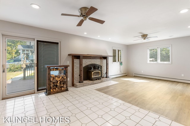 unfurnished living room featuring a wood stove, light wood-type flooring, ceiling fan, and baseboard heating