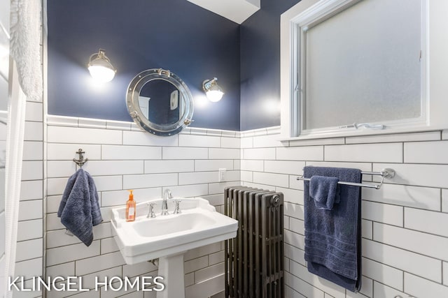 bathroom with tile walls, radiator, and sink