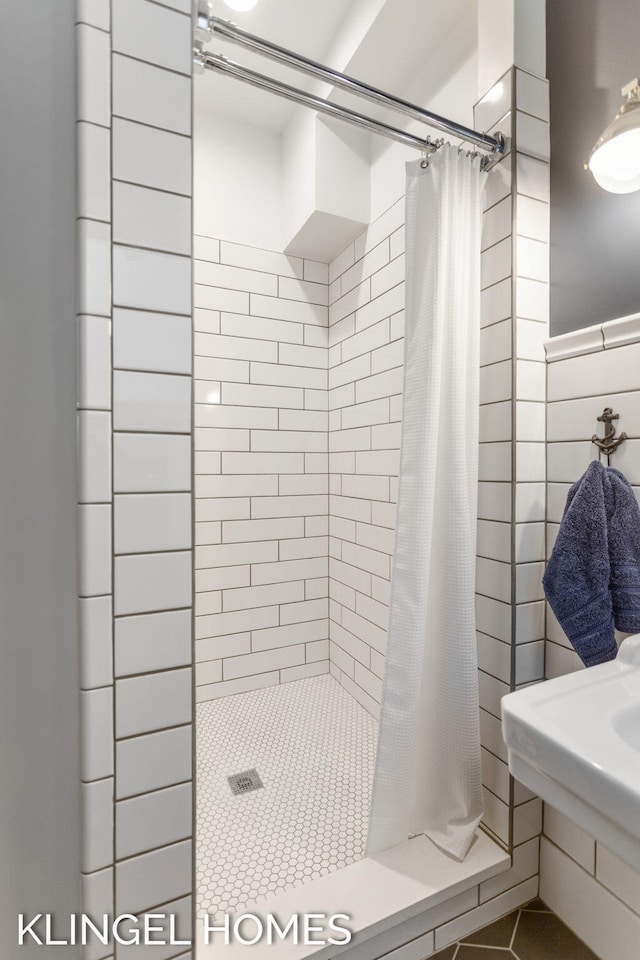 bathroom with a shower with shower curtain and tile walls