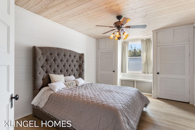 bedroom with light hardwood / wood-style flooring, radiator, wooden walls, ceiling fan, and wooden ceiling