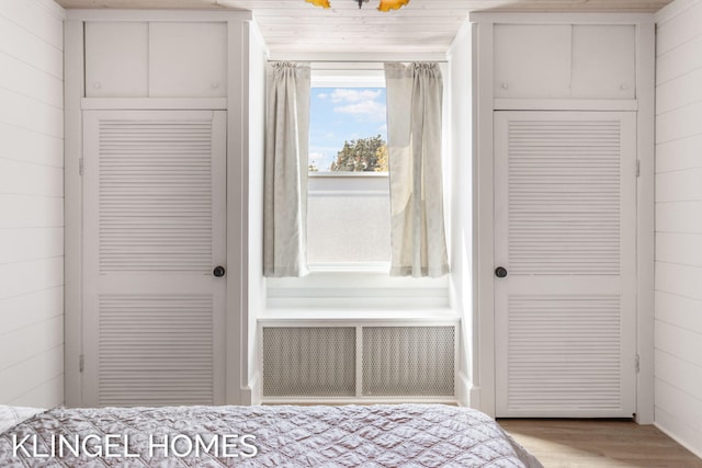 unfurnished bedroom featuring wood walls, radiator, and light hardwood / wood-style flooring