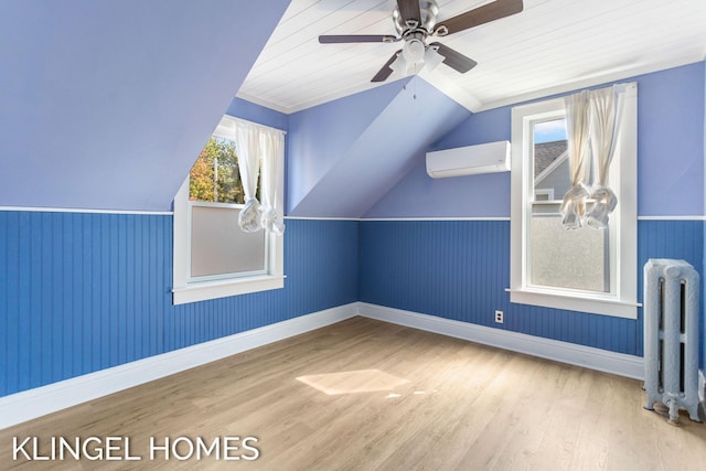 bonus room with hardwood / wood-style flooring, an AC wall unit, lofted ceiling, radiator heating unit, and ceiling fan