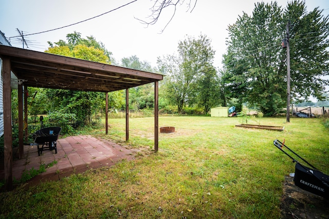 view of yard with a storage shed, a patio area, and a fire pit