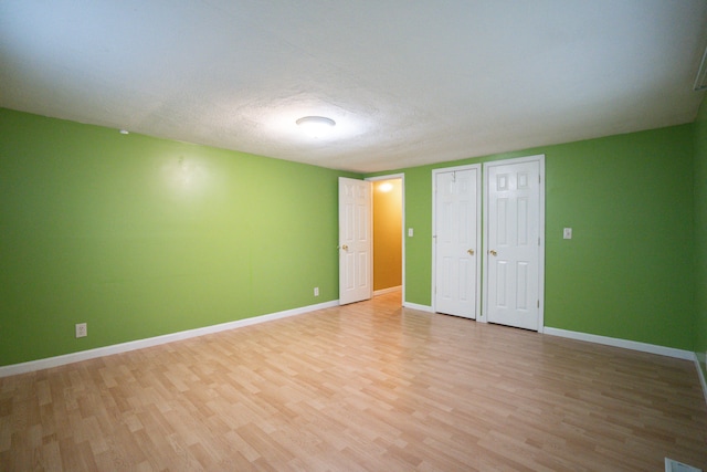 interior space featuring multiple closets, light hardwood / wood-style floors, and a textured ceiling